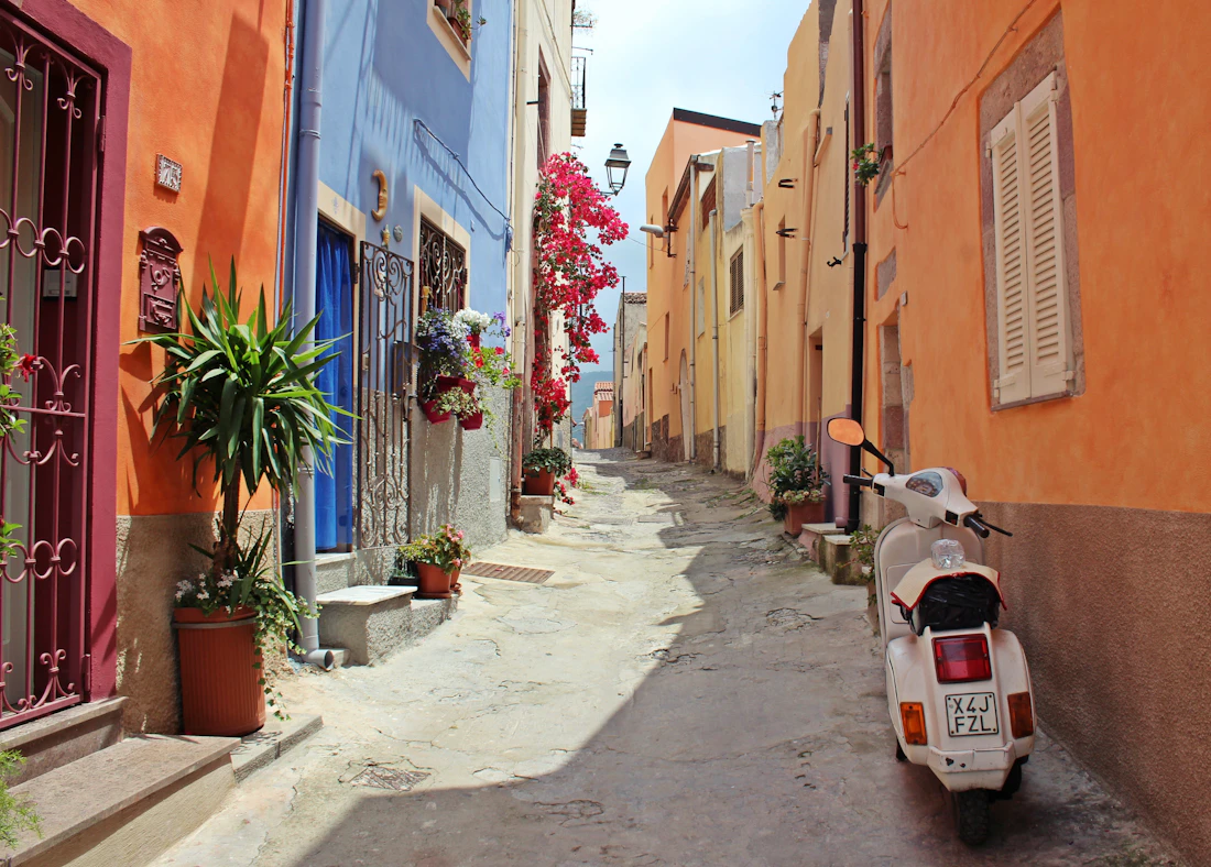 Ruelle colorée d'un village, un scooter garé devant une porte
